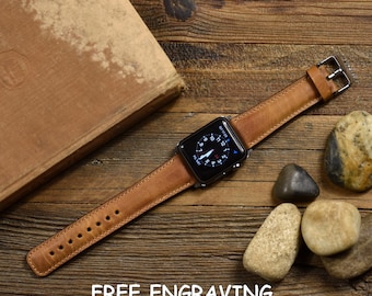 Könnte beinhalten: Ein braunes Lederarmband für eine Apple Watch. Das Armband liegt auf einer Holzoberfläche mit einem Buch und Steinen. Das Zifferblatt der Uhr zeigt die Zeit und das Datum an. Der Text "FREE ENGRAVING NEXT DAY FREE SHIPPING" befindet sich am unteren Rand des Bildes.