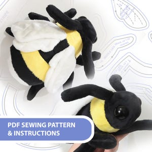 May include: A plush bee toy featuring black and yellow stripes with white wings and large black eyes, displayed alongside a printed paper sewing pattern with labels including "MIDDLE LEG" and "ANTENNA" and text "PDF SEWING PATTERN & INSTRUCTIONS".