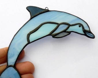 Blue dolphin in colored glass decoration. Gift ocean décor. Sun-catching marine animal in stained glass. Holiday decorations