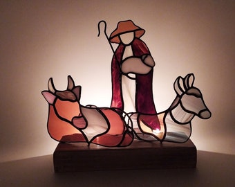 Nativity scene depicting shepherd and animals in stained glass. Original minimalist decoration for Christmas tree. Modern design style.