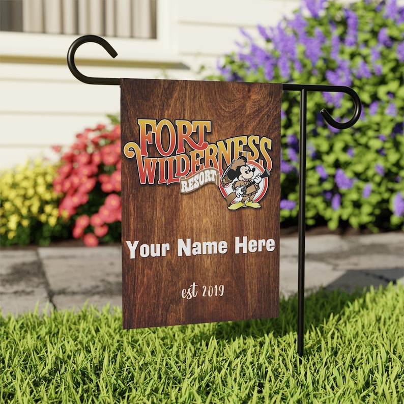 May include: A brown wooden garden flag with the text "Fort Wilderness Resort" and a cartoon image of Mickey Mouse. The text "Your Name Here" and "est 2019" are also on the flag.
