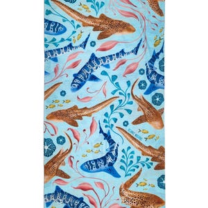Op de afbeelding: Een rechthoekige strandhanddoek met een lichtblauwe achtergrond met een herhalend patroon van bruine luipaardhaaien, blauw gevlekte haaien, kleine gele vissen, roze zeewier en blauw koraal. De tekst Oceanic Whispers staat in kleine blauwe letters.
