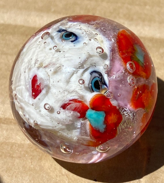 Handmade artisan glass collector's marble head Molly, with red flowers in her sparkling pink hair.