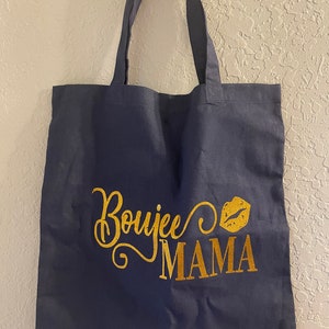 May include: A navy blue tote bag with gold glitter lettering that says "Boujee Mama" and a gold glitter lip print.