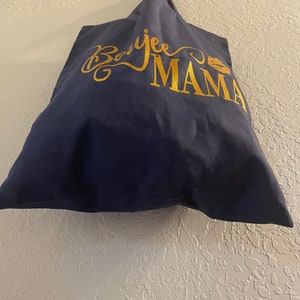 May include: A navy blue tote bag with gold lettering that says "Boojee Mama" with a gold lip print.
