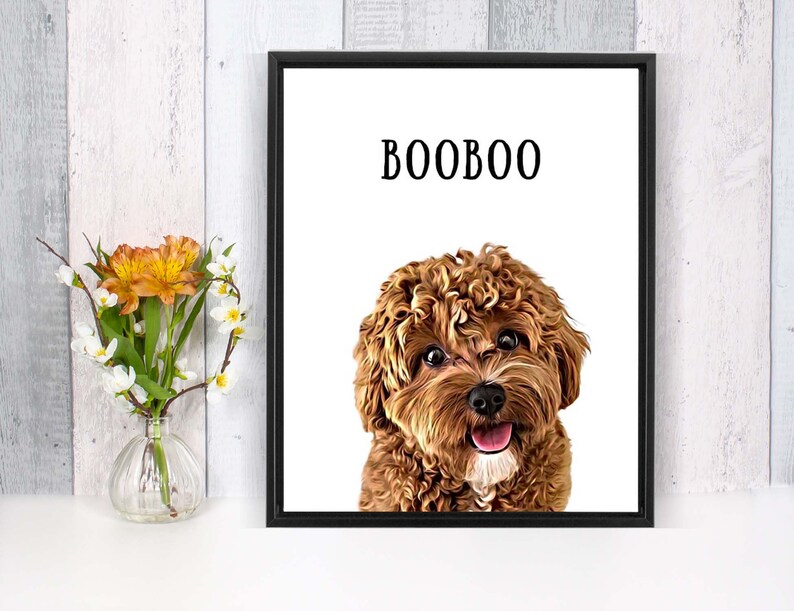 May include: A framed print of a brown and white dog with curly hair. The dog is looking at the camera and has its tongue sticking out. The print has the word "BOOBOO" written in black text at the top.