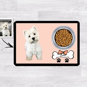 Pu&ograve; includere: Un tappetino per cibo per cani rosa e bianco con un'etichetta a forma di osso con il nome "Luna". Il tappetino presenta un'immagine di un cane bianco e una ciotola di cibo per cani.
