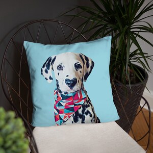 Puede incluir: Un coj&iacute;n cuadrado con un perro d&aacute;lmata con manchas negras y un pa&ntilde;uelo geom&eacute;trico colorido. El perro tiene una nariz en forma de coraz&oacute;n sobre un fondo azul claro. El coj&iacute;n est&aacute; sobre una silla de metal.