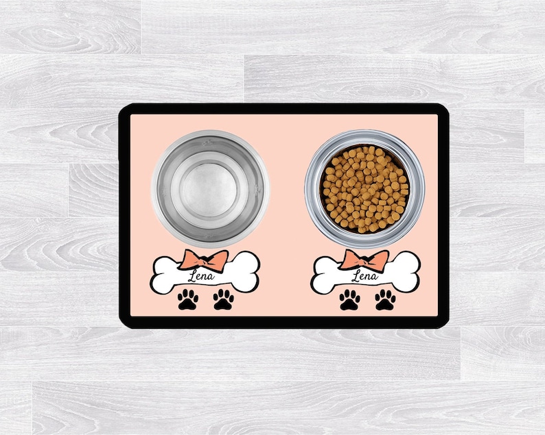 Pu&ograve; includere: Tappetino rosa per cibo per animali domestici con due ciotole in acciaio inossidabile, una piena di cibo per cani. Il tappetino ha un design a forma di osso con il nome "Lena" su ogni osso.
