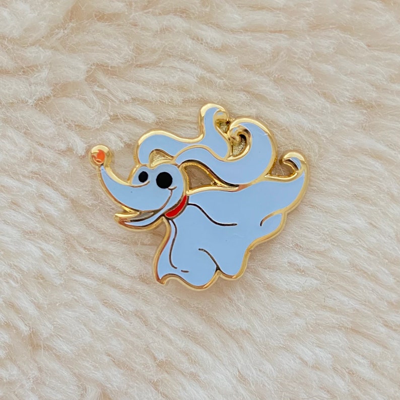 May include: A gold-colored enamel pin featuring a cartoon ghost dog with a red collar and a white body. The dog is in a running pose with its tongue sticking out.