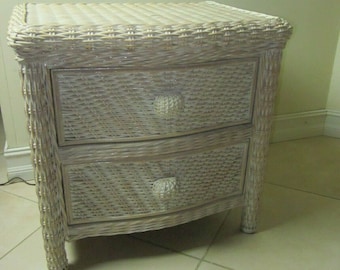 May include: White wicker nightstand with two drawers and rounded edges. The nightstand has a woven design and simple knob pulls.