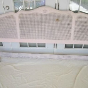 May include: A white painted headboard with a woven cane design. The headboard is made of wood and has a simple, elegant design.