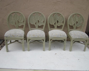 May include: Four light green wicker chairs with floral patterned cushions. The chairs have a unique design with a leaf motif on the back.