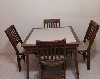 May include: A square dining table with a light-colored top and a dark wood frame, accompanied by four matching chairs. Each chair features a slatted backrest and a light-colored upholstered seat cushion, providing a coordinated furniture set.