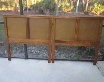 May include: A wooden headboard with a woven cane panel. The headboard is made of light brown wood and has a simple design.
