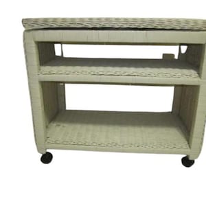 May include: White wicker rolling cart with three shelves and black wheels.