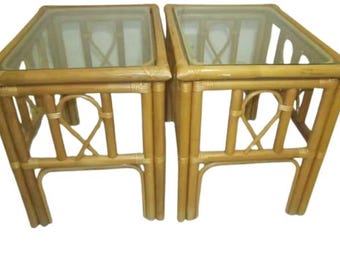 May include: Two matching natural bamboo end tables with glass tops. The tables have a woven design and are in good condition.