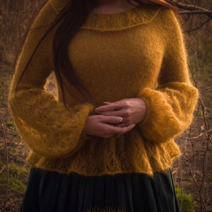 May include: Mustard yellow knit sweater with long, flared sleeves. The sweater has a round neckline and a slightly flared hem. The bottom half of the image shows a dark green skirt. The Forest Luna logo is visible at the bottom.
