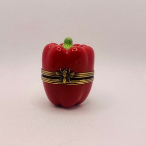 Könnte beinhalten: Eine rote Keramik-Schmuckdose in Form einer Paprika mit einem goldenen Bienen-Design auf dem Deckel.