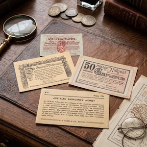 Peut inclure: Une collection de billets de monnaie d'urgence autrichienne Notgeld, incluant un billet de 50 Heller, accompagnée d'une loupe, de plusieurs pièces métalliques et d'une carte descriptive intitulée Austrian Emergency Money au prix de 25c.