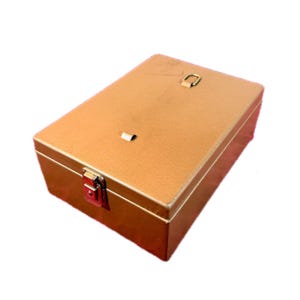 May include: A rectangular, gold-coloured metal box with a hinged lid and a latch closure. The box has a small handle on the top and a red-coloured latch. The box is likely used for storage.