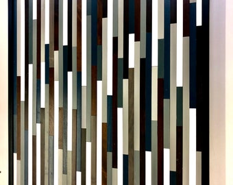 May include: A framed wall art piece made of wood slats in various shades of blue, gray, white, and brown. The slats are arranged in a vertical pattern, creating a modern and abstract design.