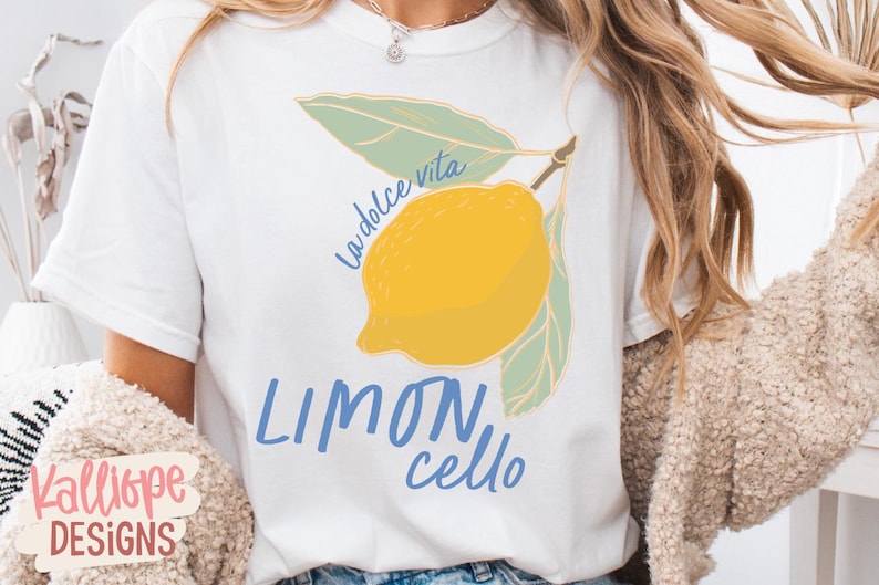 K&ouml;nnte beinhalten: Wei&szlig;es T-Shirt mit einer gelben Zitronenillustration, gr&uuml;nen Bl&auml;ttern und dem Text "La dolce vita" und "Limoncello" in Blau. Ein l&auml;ssiges Kleidungsst&uuml;ck.