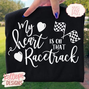 Könnte beinhalten: Ein schwarzes T-Shirt mit weißem Text, der My heart is on that Racetrack lautet, begleitet von zwei weißen Herzsymbolen und zwei karierten Rennflaggen. Ein kleines weißes kreisförmiges Abzeichen in der Ecke zeigt den Text SVG DXF PNG.