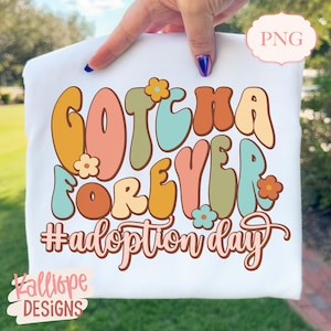 May include: White t-shirt with the text "Gotcha Forever #adoption day" in retro-style lettering. The design features various colors, including orange, pink, green, and blue, with flower accents. The shirt also has the text "PNG" in the upper right corner and "Kalliope Designs" in the lower left corner.