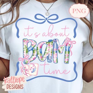 May include: White t-shirt with the phrase "it's about BAM time" in pink script and floral-patterned letters. The design includes a blue bow and a pink tag with a bird illustration. The brand name "Kalliope DESIGNS" is at the bottom.