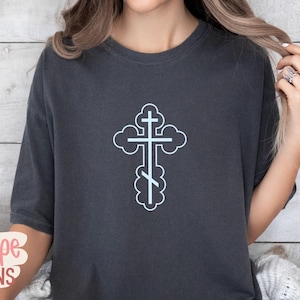 Op de afbeelding: Donkergrijs T-shirt met een lichtblauw orthodox kruisontwerp. Het kruis is omlijnd met een wolkvorm. Het shirt heeft korte mouwen en een ronde hals. De merknaam "Kalliope DESIGNS" is linksonder zichtbaar.