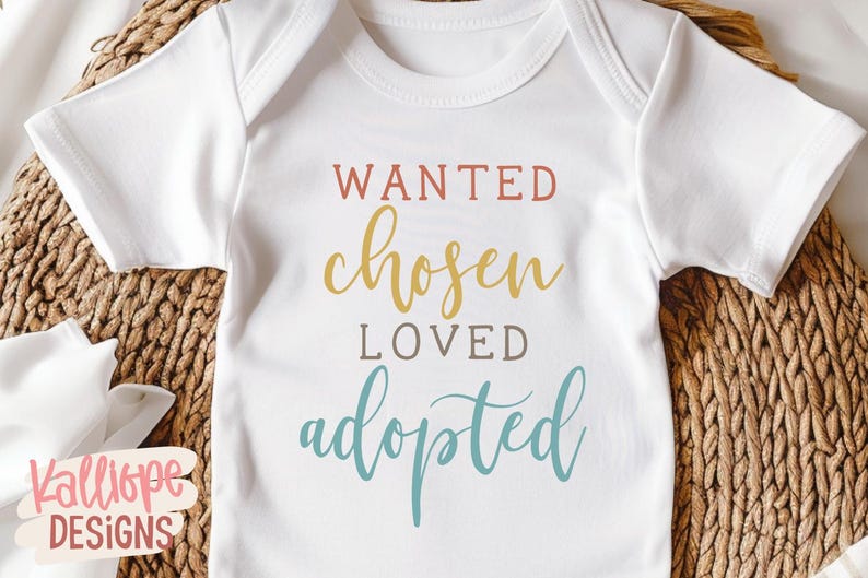 May include: White baby bodysuit with the words "WANTED chosen LOVED adopted" in various colours. The bodysuit is displayed on a woven basket. The text is in a script font.