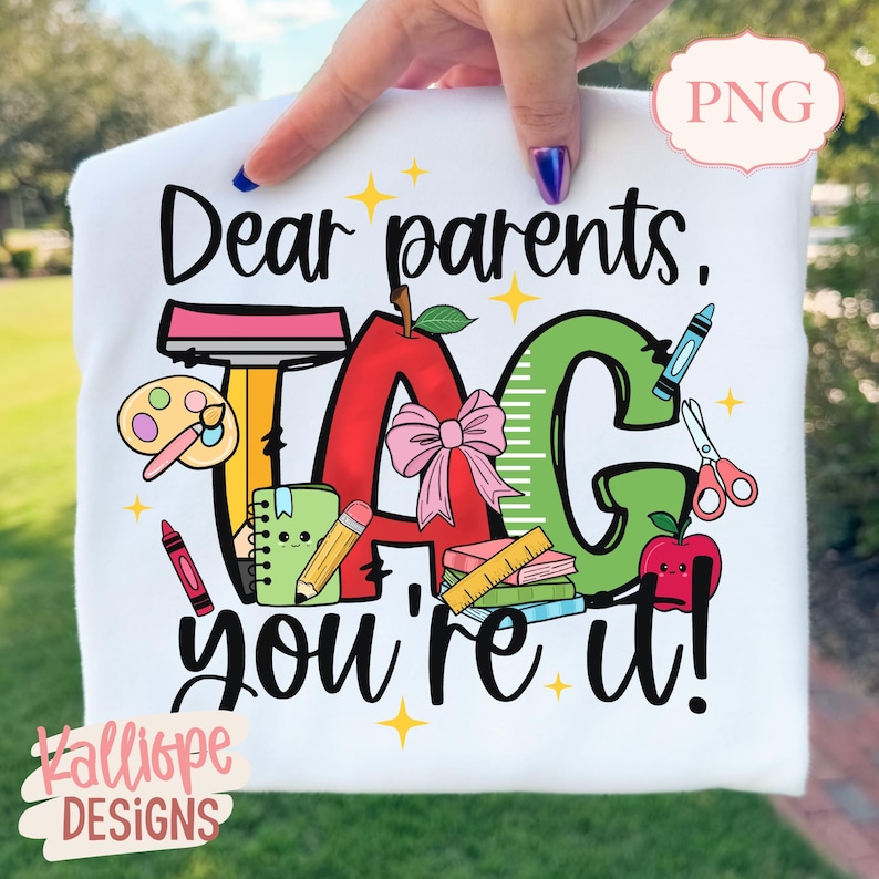 May include: White t-shirt with a colorful school-themed graphic. The design includes an apple, the word "TAG", a ruler, a crayon, and the text "Dear parents, you're it!" in black script. The design also includes a pink bow.