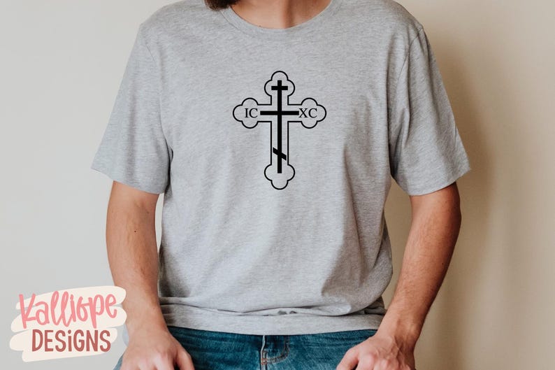 Op de afbeelding: Een lichtgrijs t-shirt met een zwart orthodox kruisontwerp. Het kruis heeft de letters IC en XC. Het t-shirt is gemaakt van een zacht materiaal en is geschikt voor dagelijks gebruik.