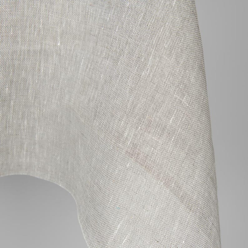 May include: Close-up of a white linen fabric with a textured weave. The fabric is soft and drapes nicely.