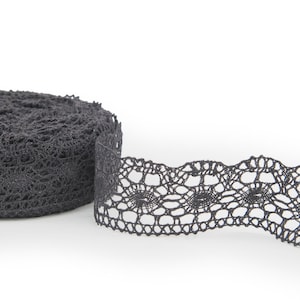 Könnte beinhalten: Eine Rolle schwarzer Spitzenborte mit einem zarten Blumenmuster. Die Spitze ist etwa 2,5 cm breit und hat einen gewellten Rand.