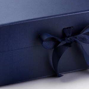 Puede incluir: Una caja de regalo azul marino con una cinta de sat&eacute;n atada en un lazo.