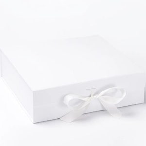 May include: A white gift box with a matching satin ribbon tied in a bow. The box is square and has a magnetic closure. Suitable for packaging gifts for special occasions.