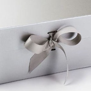 May include: A silver gift box with a satin ribbon tied in a bow. The box has a magnetic closure.