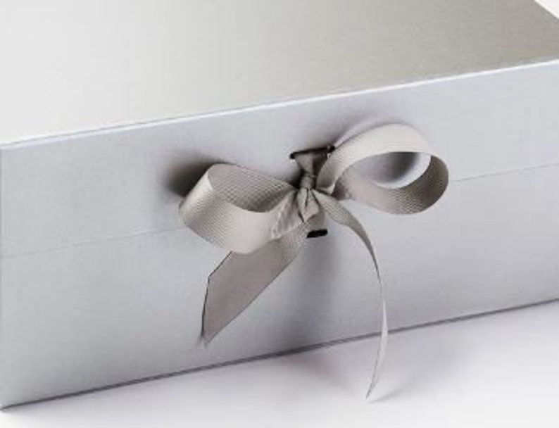 May include: A silver gift box with a satin ribbon tied in a bow. The box has a magnetic closure.