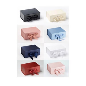 May include: Assortment of nine gift boxes in various colors, including black, white, pink, blue, and red. Each box has a satin ribbon tied in a bow.