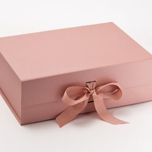 May include: A blush pink gift box with a satin finish and a matching satin ribbon tied in a bow.
