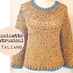 May include: A crocheted sweater in a mustard yellow color with a blue trim around the neckline and sleeves. The sweater has a loose fit and a slightly cropped length.
