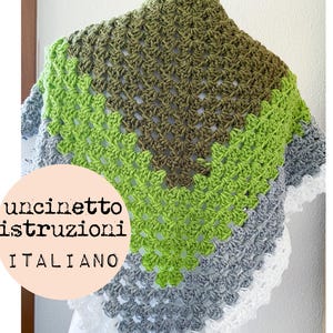 May include: A crocheted shawl in shades of green, gray, and white. The shawl is made with a granny square pattern and has a scalloped edge. The text "uncinetto istruzioni ITALIANO" is visible on the image.