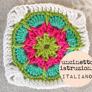 以下が含まれることがあります： 緑、ピンク、白の花柄のクロシェの正方形。正方形は白い縁取りで囲まれています。ピンクの円に「uncinetto istruzioni ITALIANO」というテキストが書かれています。