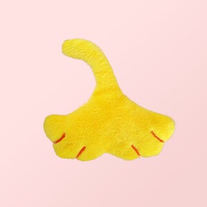 Puede incluir: Un juguete de peluche amarillo con forma de pie de dinosaurio con garras rojas.