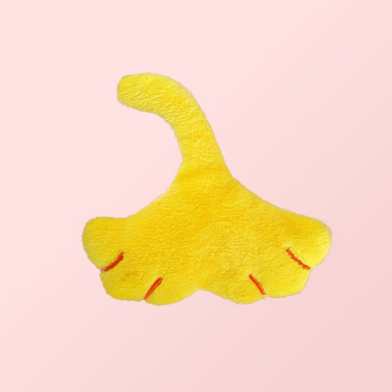 Puede incluir: Un juguete de peluche amarillo con forma de pie de dinosaurio con garras rojas.