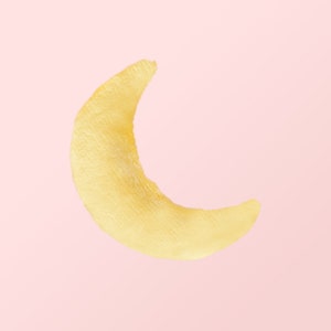 Puede incluir: Una forma de media luna amarilla hecha de material suave y peludo sobre un fondo rosa.