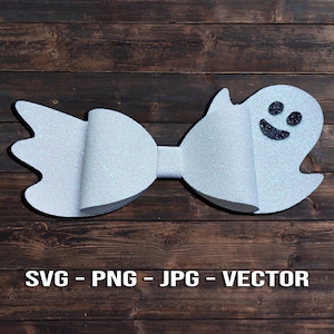 Op de afbeelding: Een witte glitter strik met een spookgezicht aan de ene kant. Het spook heeft een zwart lachend gezicht.