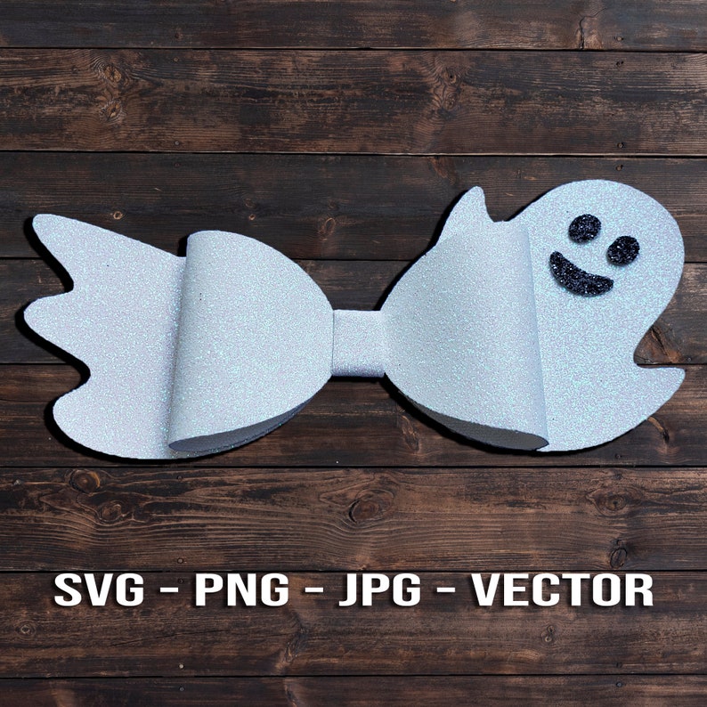 Op de afbeelding: Een witte glitter strik met een spookgezicht aan de ene kant. Het spook heeft een zwart lachend gezicht.